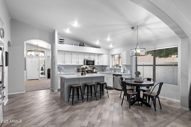 2111 E Rawhide St, Gilbert, AZ 85296 - dining room with vaulted ceiling, a chandelier, arched walkways, light wood finished floors, and recessed lighting