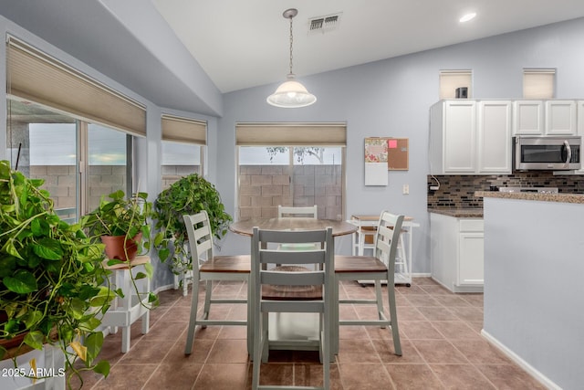 tiled dining area featuring vaulted ceiling