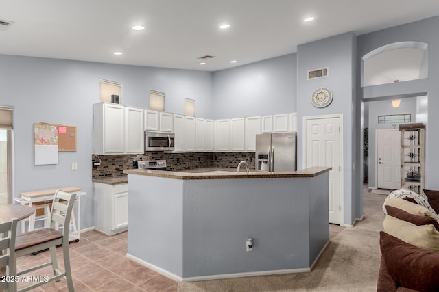 kitchen with a center island with sink, white cabinets, stainless steel appliances, and high vaulted ceiling