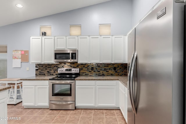 kitchen featuring light stone countertops, appliances with stainless steel finishes, tasteful backsplash, vaulted ceiling, and white cabinetry