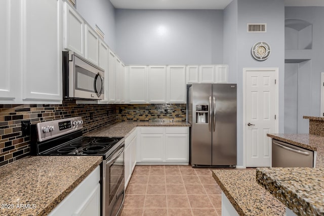 kitchen featuring backsplash, light stone countertops, white cabinetry, and stainless steel appliances