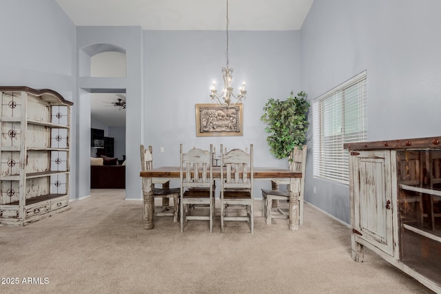 dining area with a towering ceiling, carpet, and ceiling fan with notable chandelier