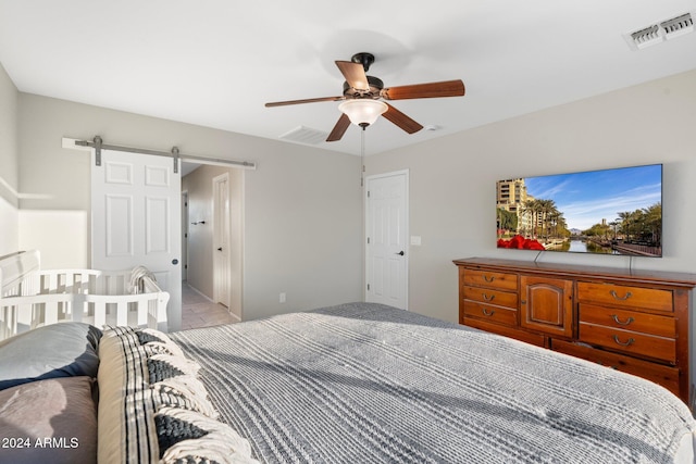 bedroom with ceiling fan and a barn door