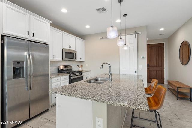 kitchen featuring stainless steel appliances, an island with sink, a barn door, and sink