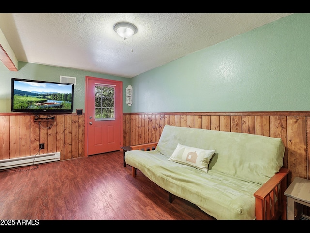 6869 W Ute Trl, Pine, AZ 85544 - living area with wainscoting, a baseboard heating unit, wood walls, wood finished floors, and a textured ceiling