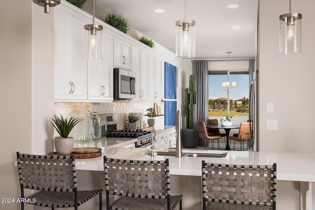 kitchen with appliances with stainless steel finishes, backsplash, white cabinets, and decorative light fixtures