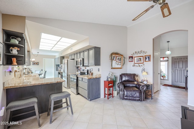 kitchen with sink, stainless steel appliances, kitchen peninsula, a textured ceiling, and a kitchen bar