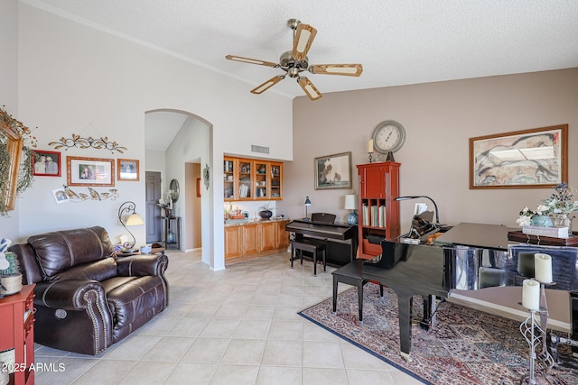 tiled living room with a textured ceiling, vaulted ceiling, and ceiling fan