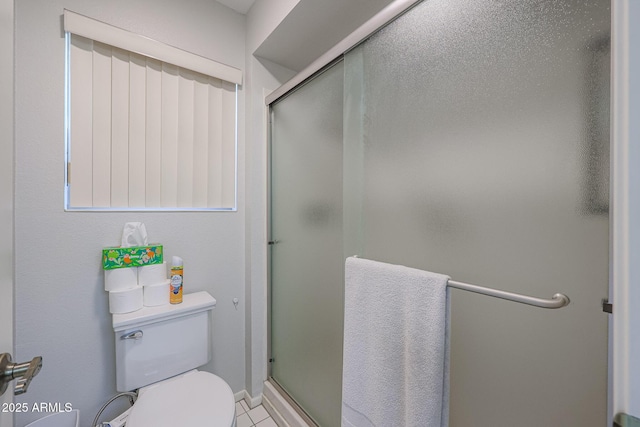 bathroom with tile patterned floors, toilet, and a shower with shower door