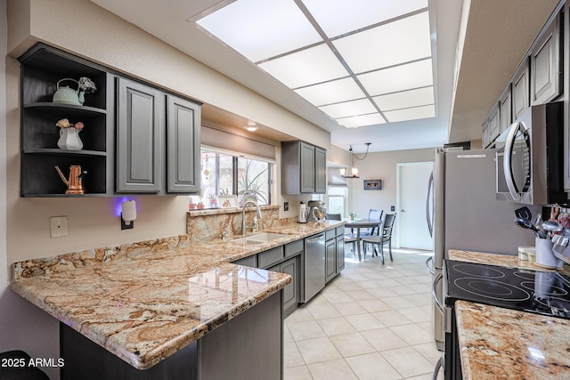 kitchen with light stone countertops, sink, kitchen peninsula, gray cabinets, and appliances with stainless steel finishes