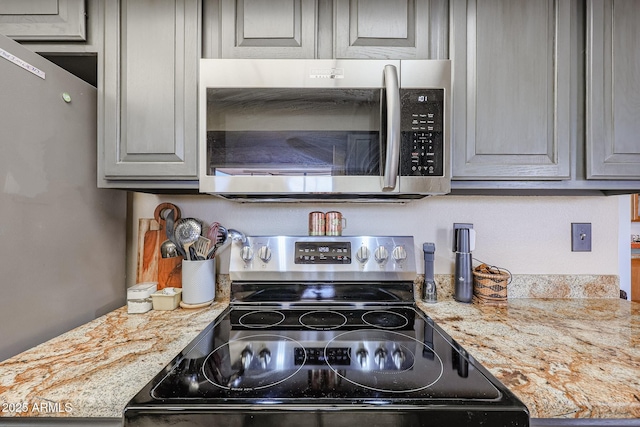 kitchen featuring gray cabinetry, light stone countertops, and appliances with stainless steel finishes