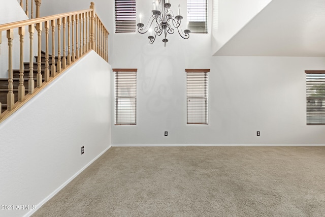 unfurnished living room with a towering ceiling, carpet floors, and a chandelier