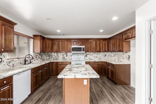 kitchen with decorative backsplash, white appliances, a center island, and dark hardwood / wood-style floors