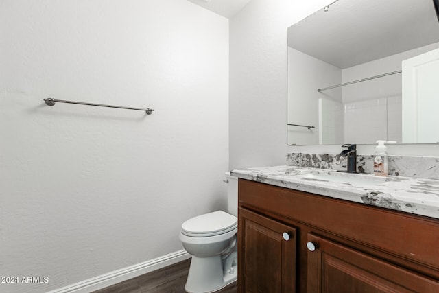 bathroom featuring wood-type flooring, vanity, toilet, and walk in shower