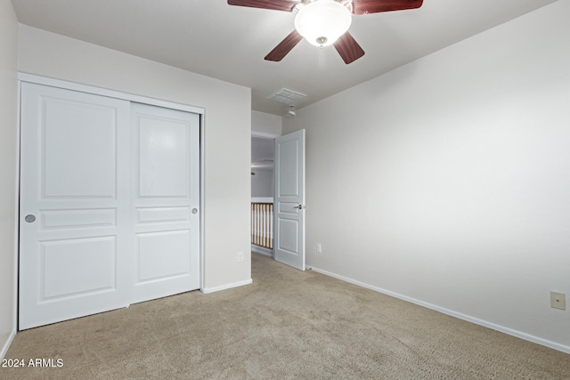 unfurnished bedroom with ceiling fan, light carpet, and a closet