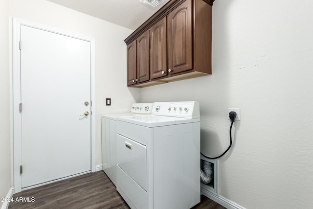 clothes washing area with washing machine and dryer, cabinets, and dark wood-type flooring