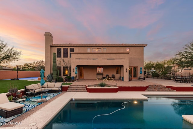 9753 E Suncrest Rd, Scottsdale, AZ 85262 - back of property at dusk with outdoor lounge area, a patio area, an outdoor pool, a chimney, and stucco siding