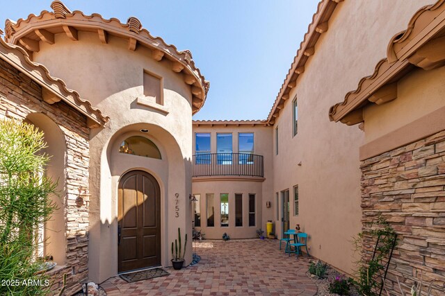 9753 E Suncrest Rd, Scottsdale, AZ 85262 - view of exterior entry with a patio, stucco siding, stone siding, and a balcony