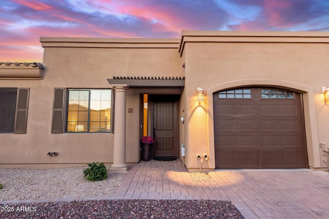 view of front of property featuring decorative driveway, a garage, and stucco siding