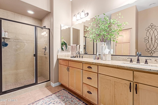 bathroom featuring a sink, double vanity, a shower stall, and tile patterned flooring