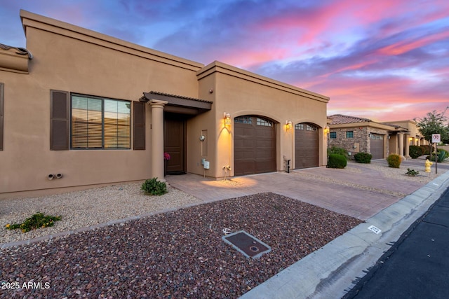 view of front of house featuring decorative driveway, a garage, and stucco siding