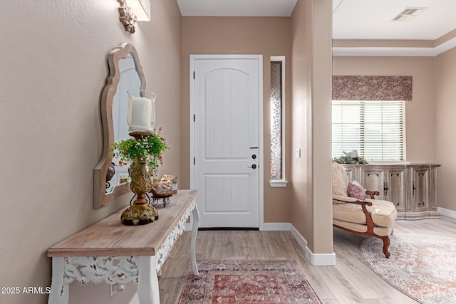 foyer entrance with visible vents, baseboards, and light wood-style floors