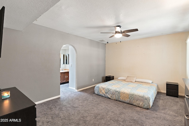 carpeted bedroom featuring ceiling fan, ensuite bathroom, and a textured ceiling