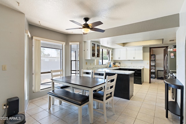 tiled dining space featuring a textured ceiling and ceiling fan