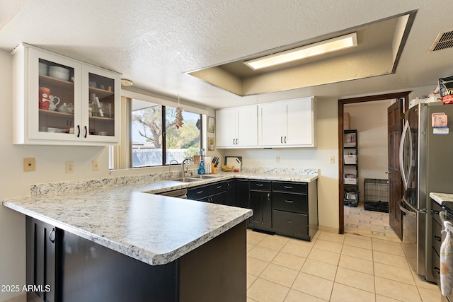 kitchen featuring a raised ceiling, white cabinetry, sink, and stainless steel fridge