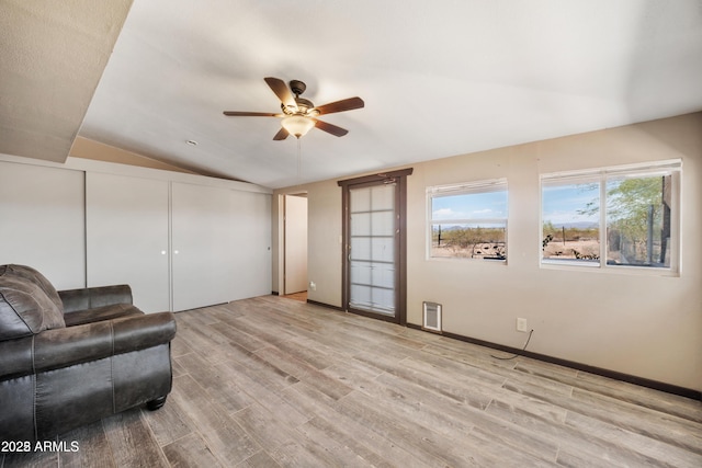 living room featuring a wealth of natural light, ceiling fan, light wood finished floors, and vaulted ceiling