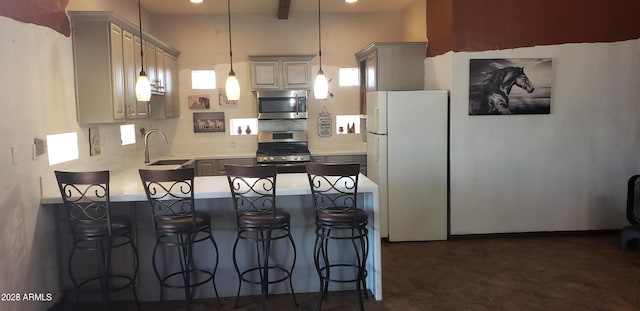 kitchen with a kitchen bar, a peninsula, light countertops, hanging light fixtures, and appliances with stainless steel finishes