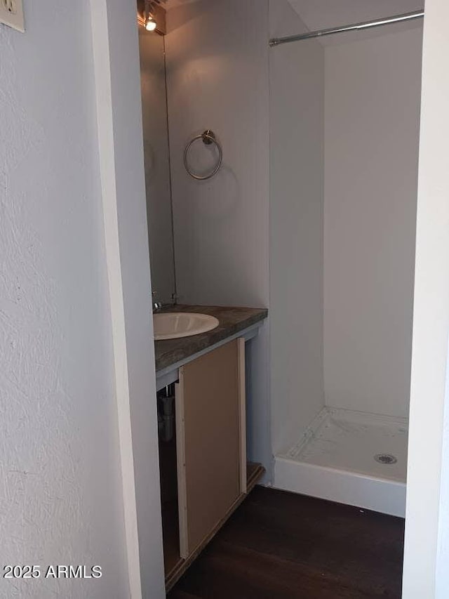 bathroom with wood finished floors, vanity, and a stall shower
