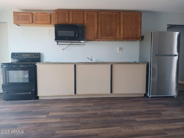 kitchen featuring brown cabinetry, black appliances, dark wood-type flooring, and a sink