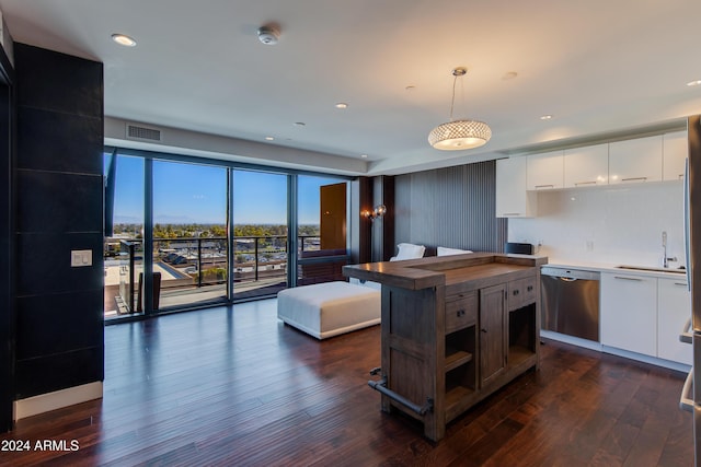 kitchen featuring pendant lighting, stainless steel dishwasher, white cabinets, and sink