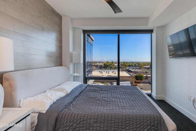 bedroom with ceiling fan, multiple windows, and wood walls