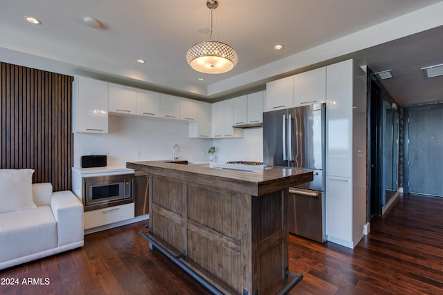 kitchen featuring hanging light fixtures, white cabinets, stainless steel appliances, and a center island