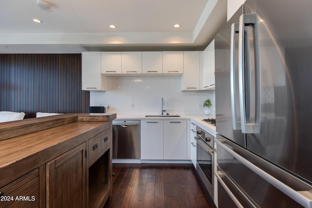 kitchen featuring stainless steel appliances, white cabinets, wooden counters, and sink