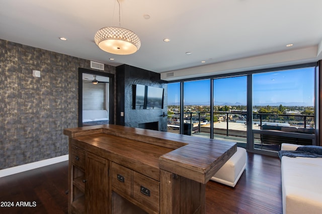 kitchen with wood counters, decorative light fixtures, dark wood-type flooring, a large fireplace, and ceiling fan