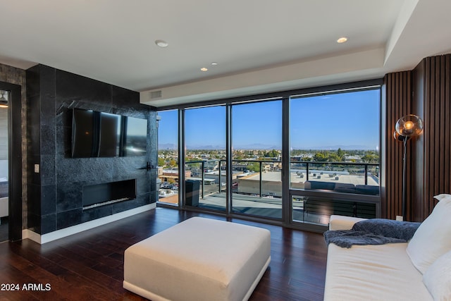 living room with dark wood-type flooring, a large fireplace, floor to ceiling windows, and plenty of natural light