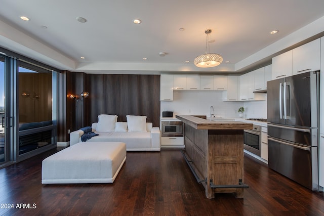 kitchen featuring decorative light fixtures, dark hardwood / wood-style floors, a kitchen island, appliances with stainless steel finishes, and white cabinets