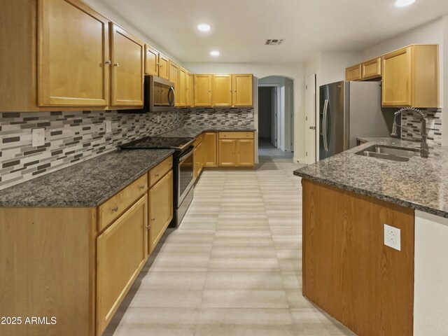 13033 W Avalon Dr, Avondale, AZ 85392 - kitchen with dark stone counters, decorative backsplash, sink, and stainless steel appliances