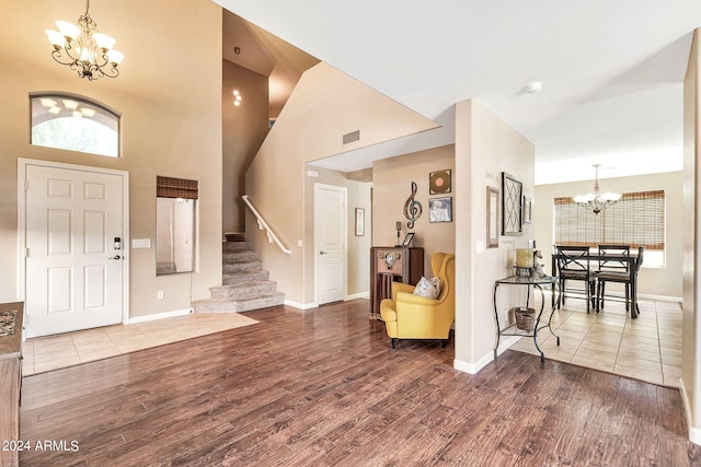 foyer entrance featuring a towering ceiling, a chandelier, and hardwood / wood-style floors