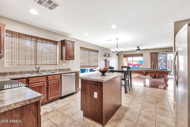 kitchen with decorative light fixtures, appliances with stainless steel finishes, a wealth of natural light, and a center island