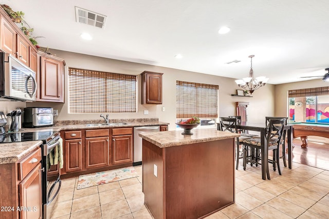 kitchen with sink, decorative light fixtures, stainless steel appliances, a center island, and a wealth of natural light