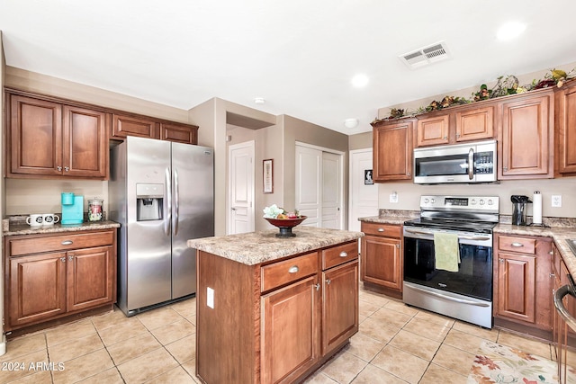 kitchen featuring light stone counters, appliances with stainless steel finishes, light tile patterned floors, and a center island