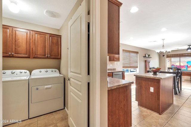 laundry area featuring washing machine and clothes dryer, light tile patterned floors, a chandelier, and cabinets