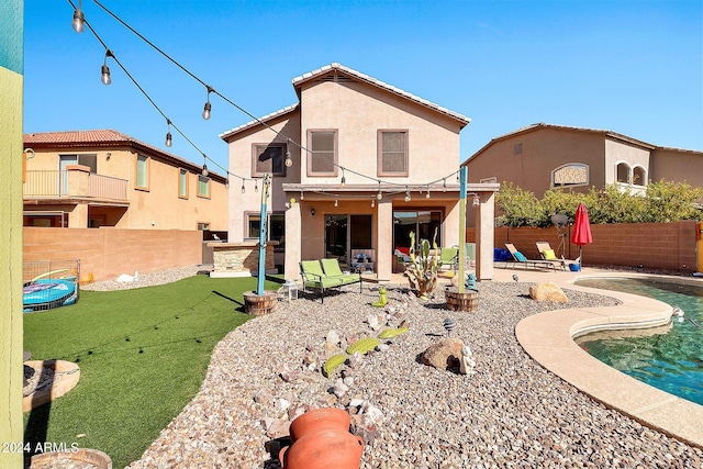 back of house with a patio, a lawn, and a balcony