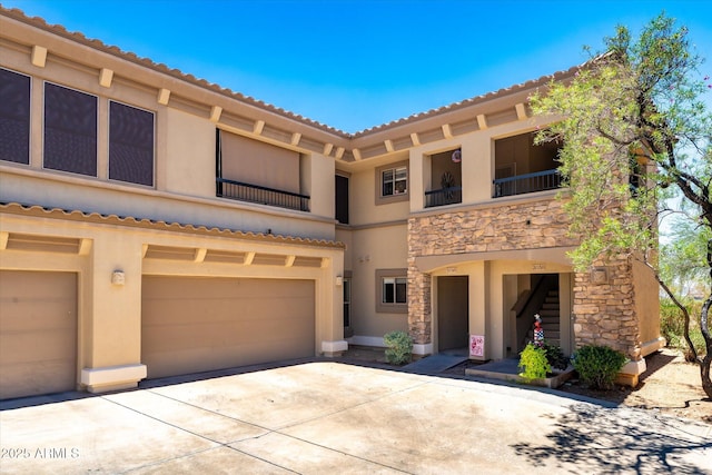 19700 N 76th St Unit 1038, Scottsdale, AZ 85255 - view of front of property with stone siding, stucco siding, driveway, a balcony, and a garage