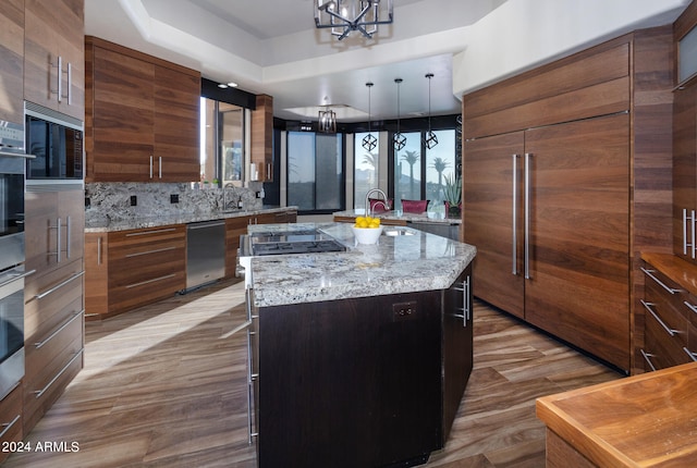 kitchen featuring an inviting chandelier, light stone countertops, stainless steel appliances, and a kitchen island