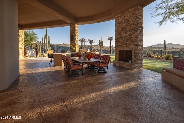 view of patio / terrace featuring a mountain view and an outdoor stone fireplace